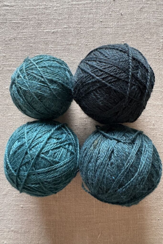Four balls of teal yarn, in different shades.