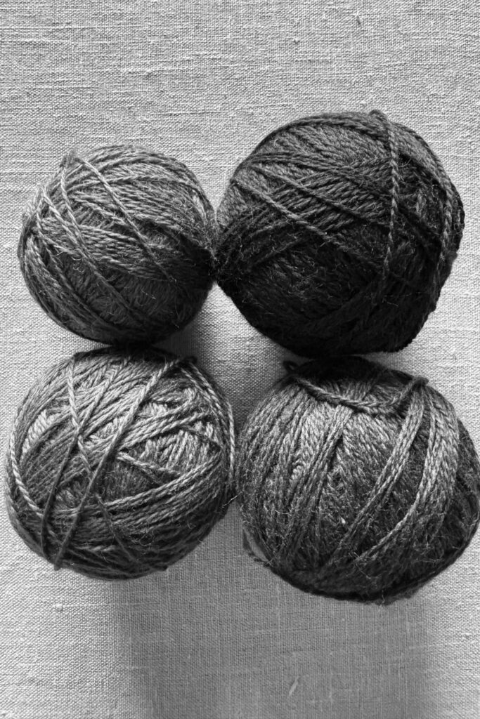 Four balls of teal yarn as a monochrome image, ideal for choosing yarn colours for crochet and knitting.