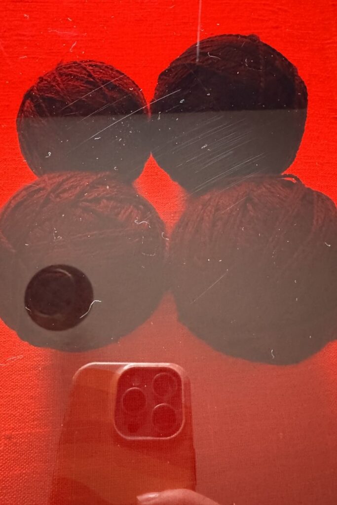 Four balls of teal yarn under red perspex, for choosing yarn colours.