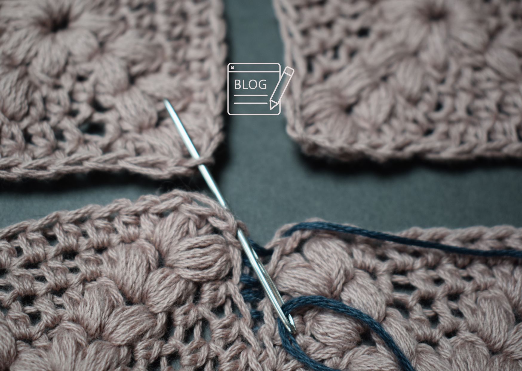 Close up of four pink crocheted squares being sewn togther.