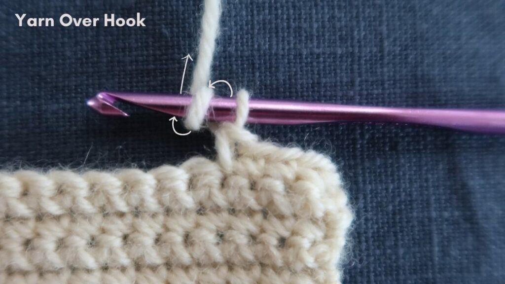 Close up of a crochet hook with swatch, showing how to yarn over.