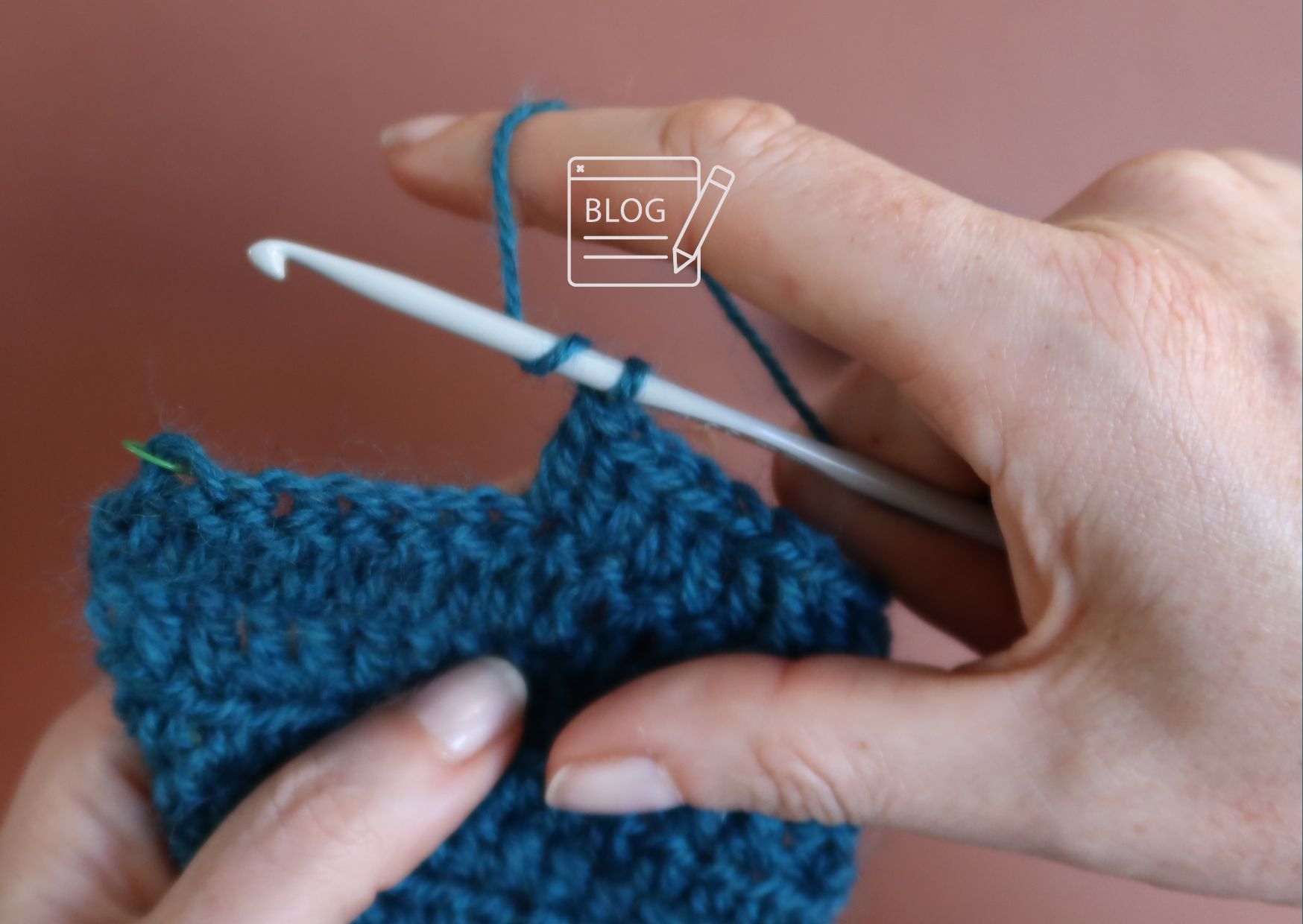 Right handed crocheter holding hook and yarn in right hand and swatch in left. 'Blog' logo as an overlay.