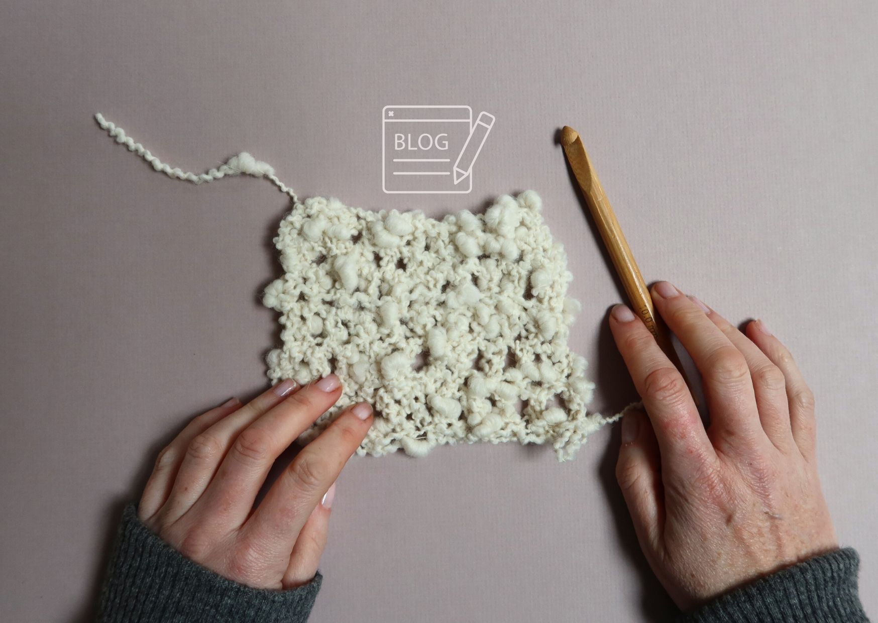 Crochet swatch of cream jumbo boucle yarn with a bamboo crochet hook and my hands in frame.