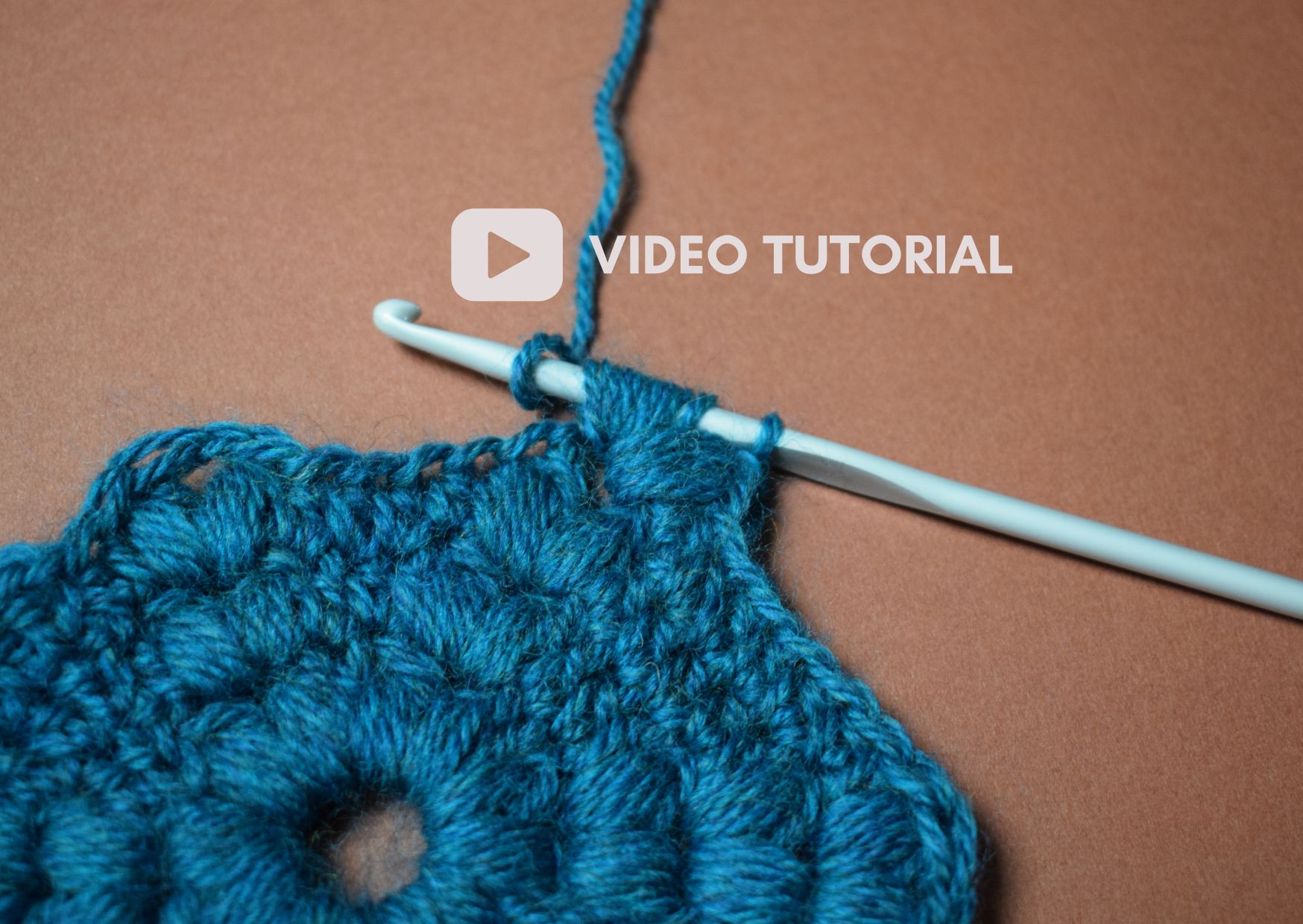 Teal coloured hexagon motif with crocheted puff stitches and 'video tutorial' as a cover title.