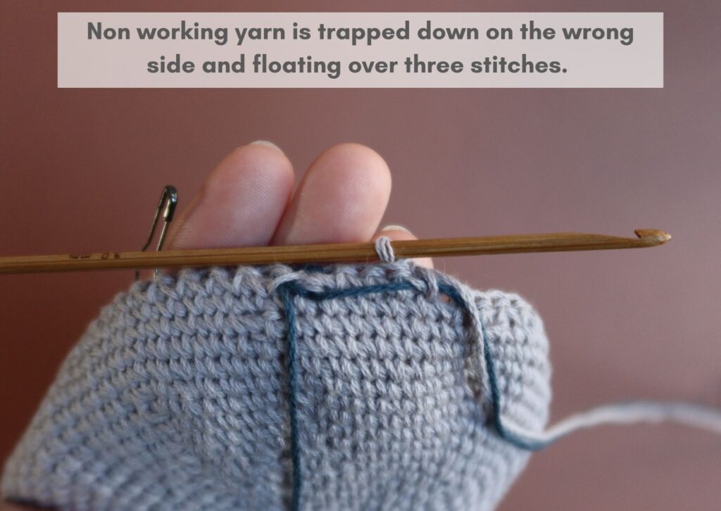 Wrong side of waistcoat stitch fabric being worked in the round with the non-working yarn trapped down.