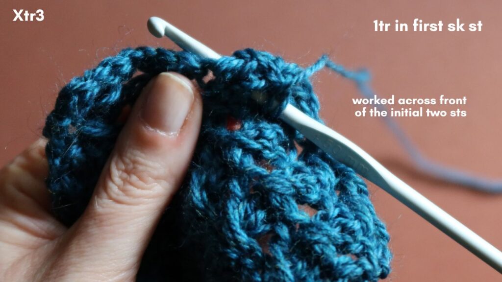Close up of the final treble crochet being made in first skipped stitch.