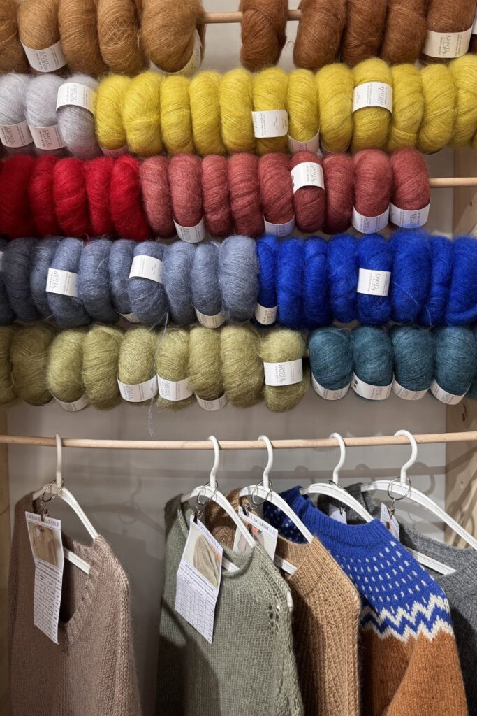 Lots of balls of mohair yarn with knitted jumper samples below.