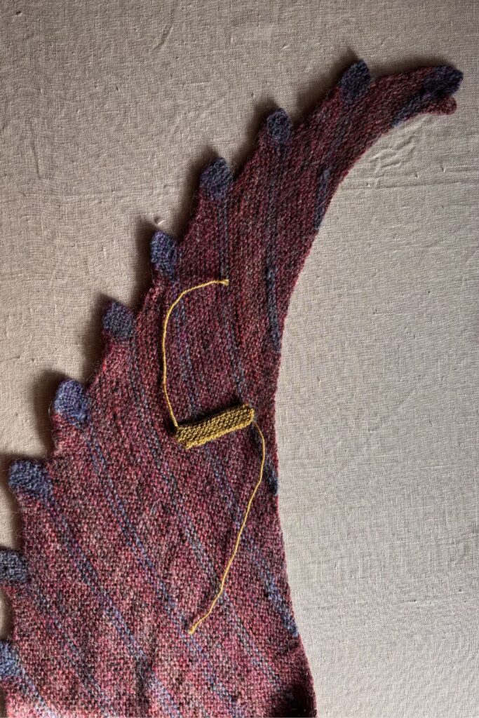 Close up of a knitted shawl with a small tab ready to be sewn on.