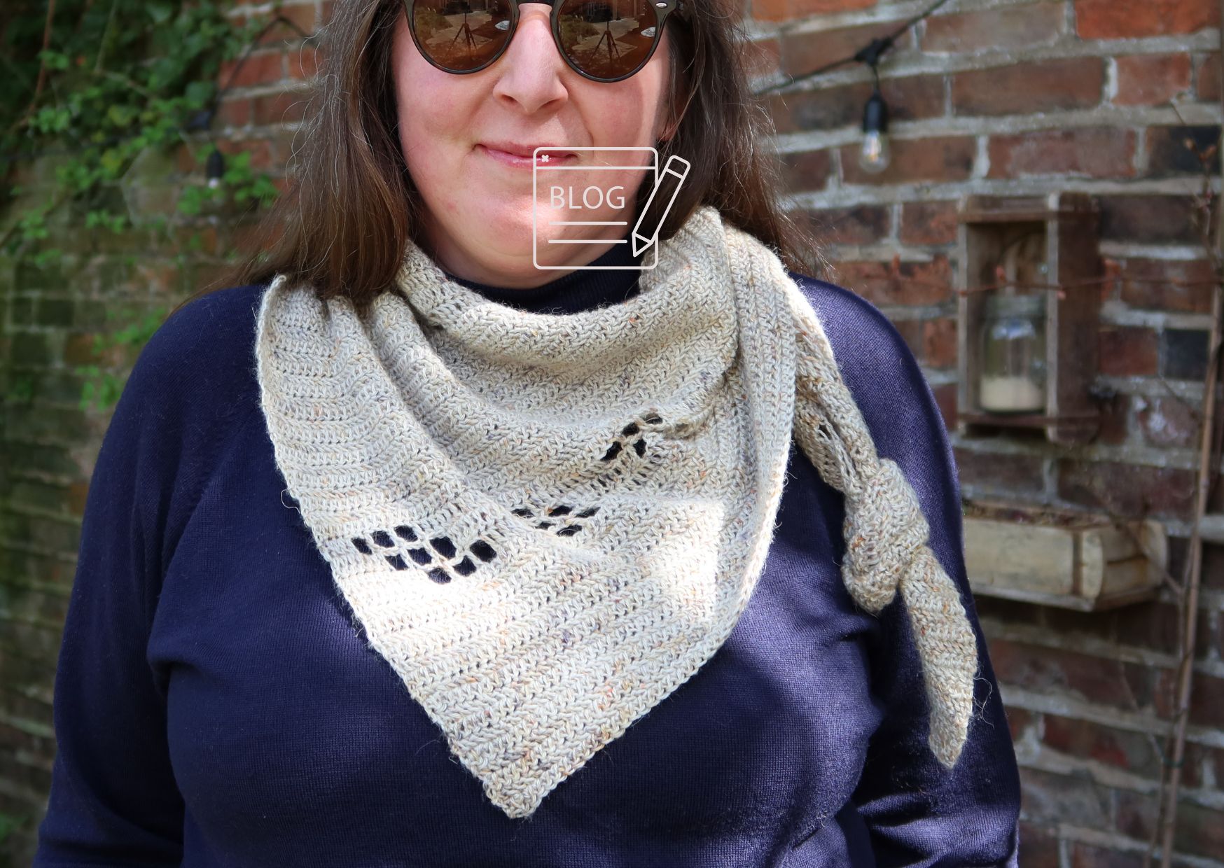 A crocheted shawl being worn outside a barn.