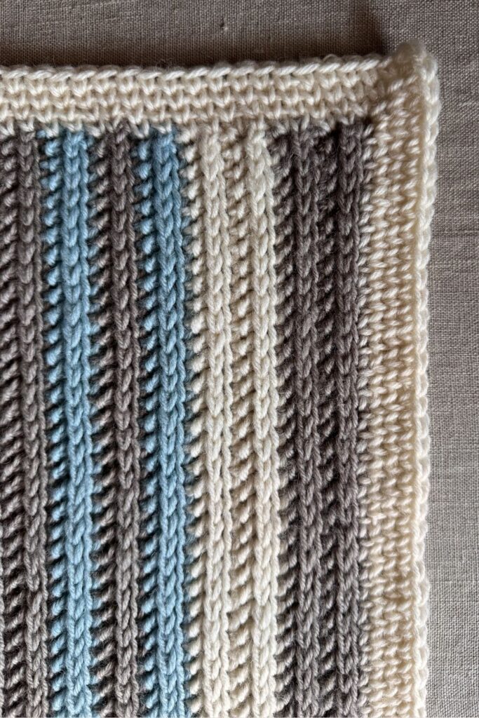 Striped crocheted Pebble Spotter blanket close up of border and blanket rows.