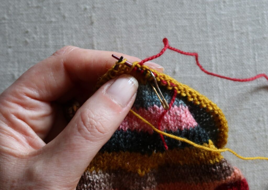 A pair of brightly coloured knitted striped trainer socks with no sew coloured yarn join method.