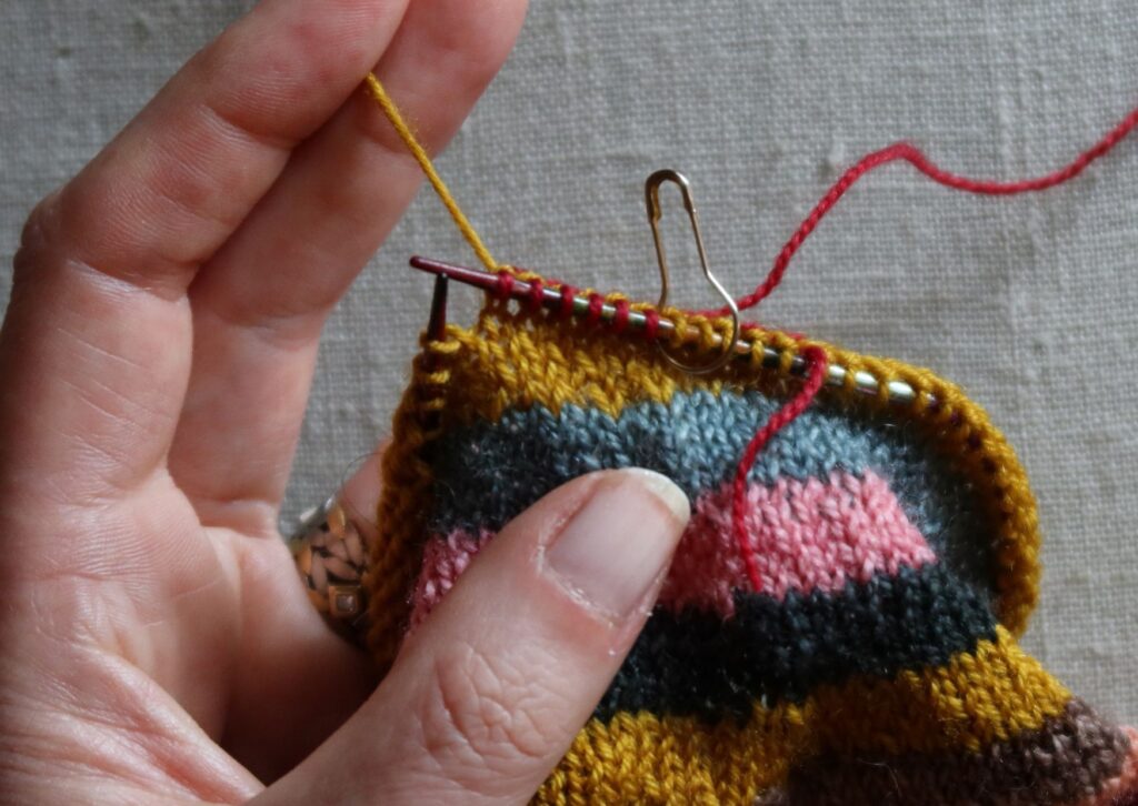 A pair of brightly coloured knitted striped trainer socks with no sew coloured yarn join method.
