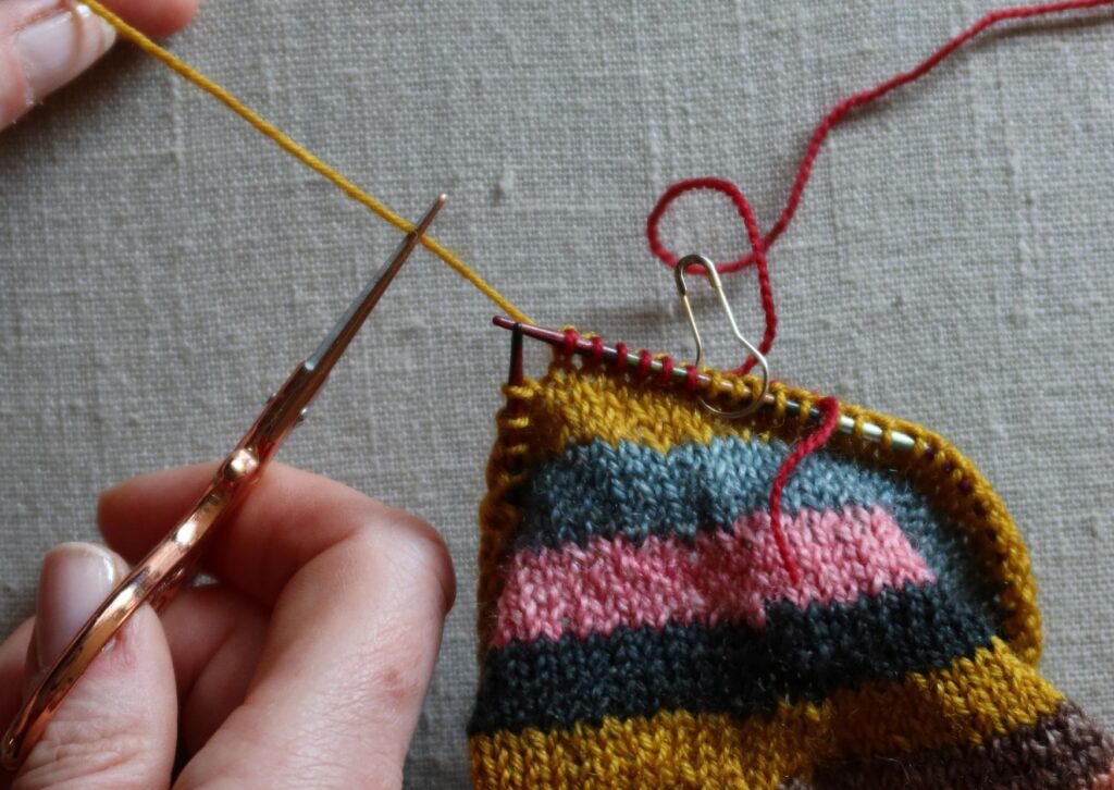 A pair of brightly coloured knitted striped trainer socks with no sew coloured yarn join method.