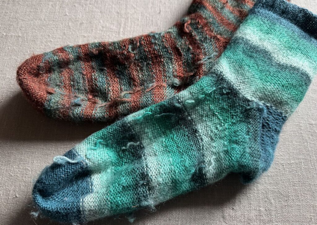 Inside of two coloured knitted striped socks with no sew coloured yarn join method.