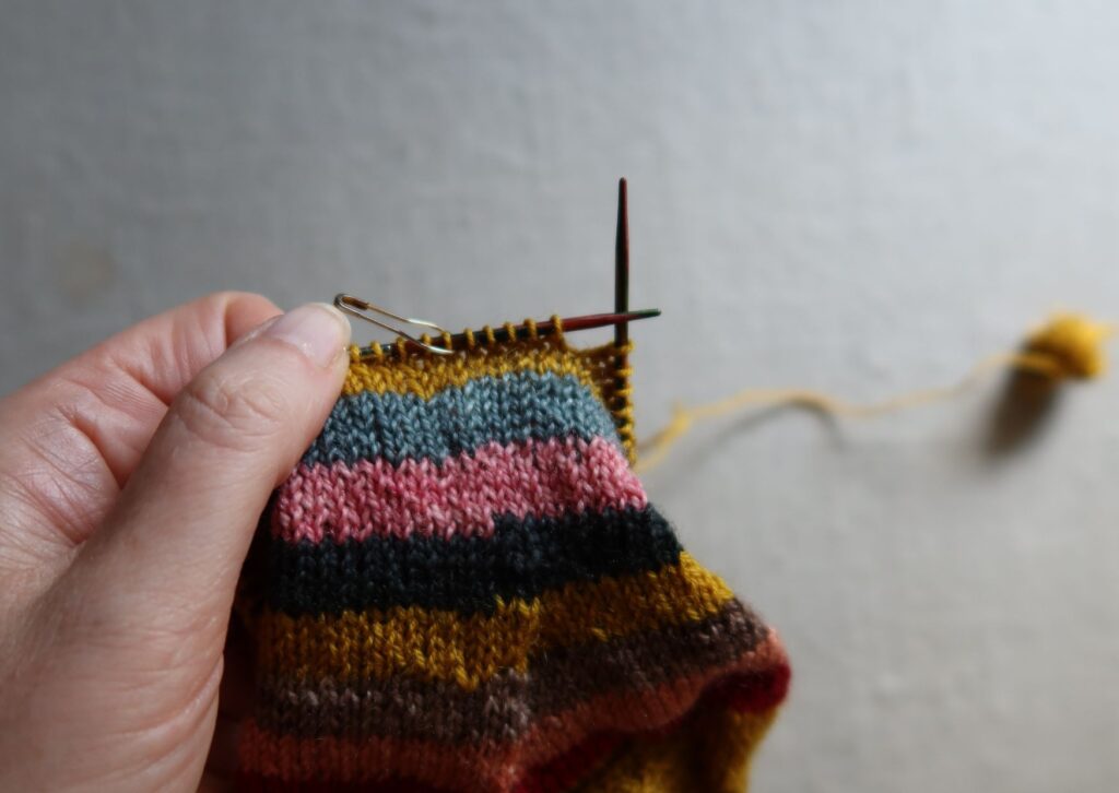 A pair of brightly coloured knitted striped trainer socks with no sew coloured yarn join method.
