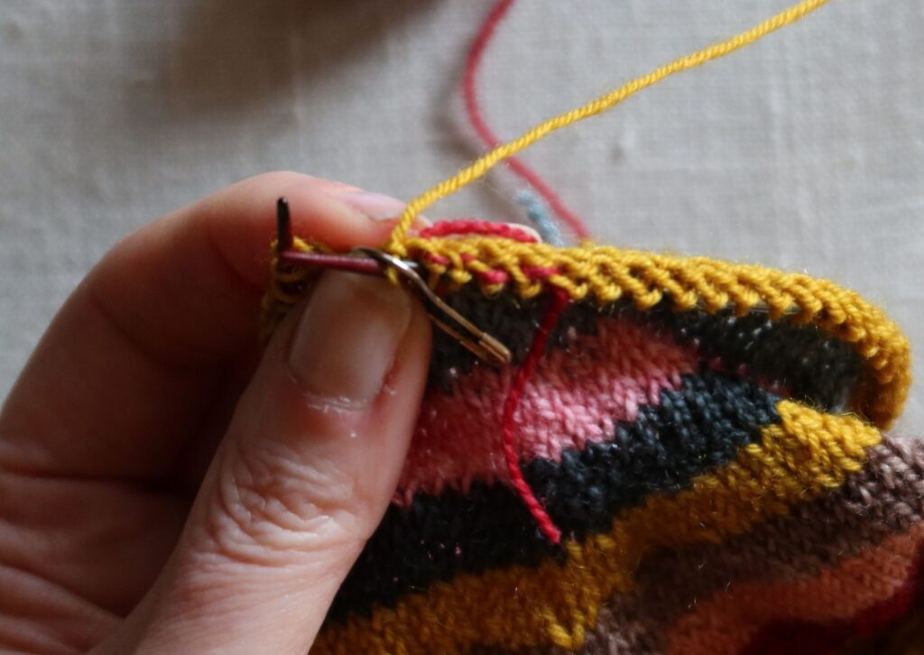 A pair of brightly coloured knitted striped trainer socks with no sew coloured yarn join method.