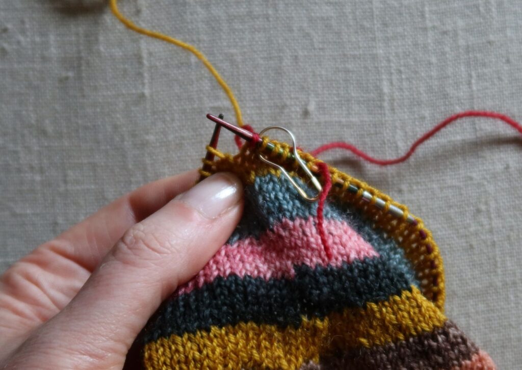 A pair of brightly coloured knitted striped trainer socks with no sew coloured yarn join method.