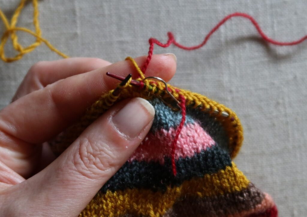 A pair of brightly coloured knitted striped trainer socks with no sew coloured yarn join method.