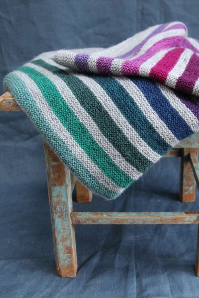 Striped knitted blanket pattern in light grey with earthy Scottish coloured stripes.