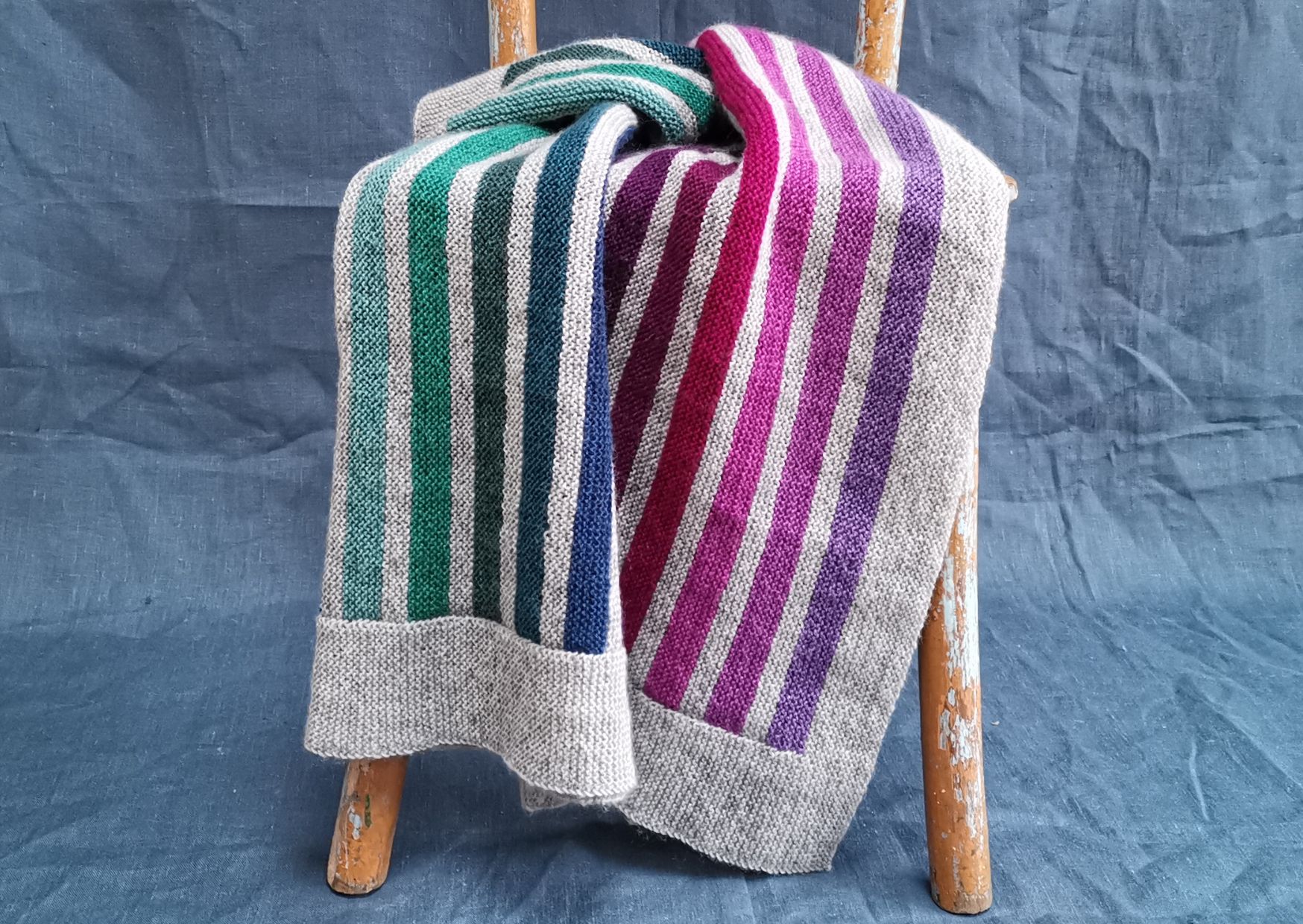 Striped knitted blanket pattern in light grey with earthy Scottish coloured stripes.