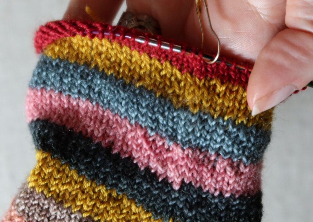 Close up of stripy trainer socks being knitted with no obvious jog in the bands of colours.