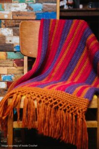 Retro striped crochet blanket with knotted fringe.